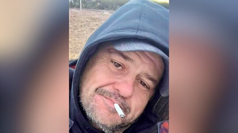 A man's face with his hood up and a cigarette hanging out of his mouth.