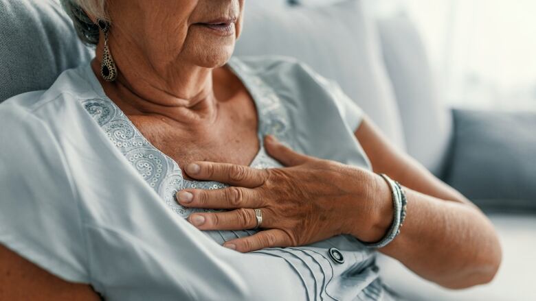 A woman clutches her chest in a stock photo.