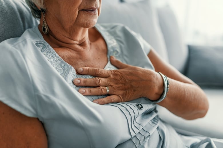 A woman clutches her chest in a stock photo.