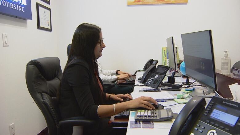 A brown woman types on a computer.