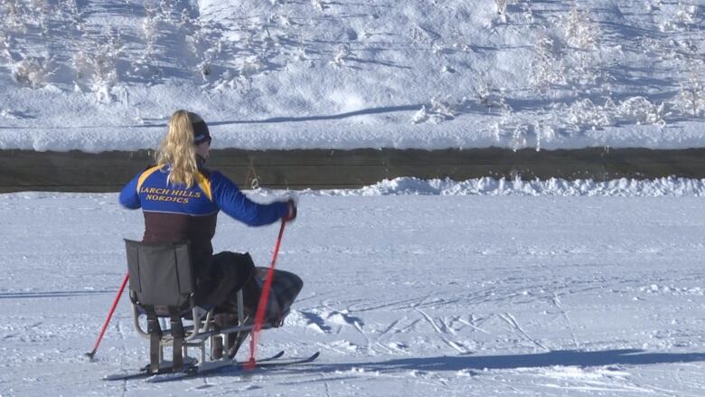 Lily Brook sit-skis away from the camera