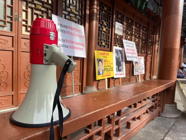 A white and red megaphone next to protest signs denouncing the police killing of 38-yar-old Ronny Kay. 