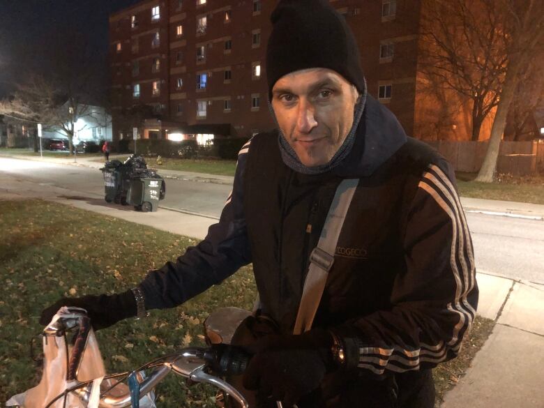 A man wearing a hat and a jacket holding a bicycle