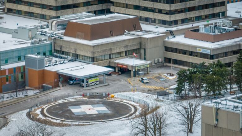 From above, a hospital helipad and entrance on a snowy day.