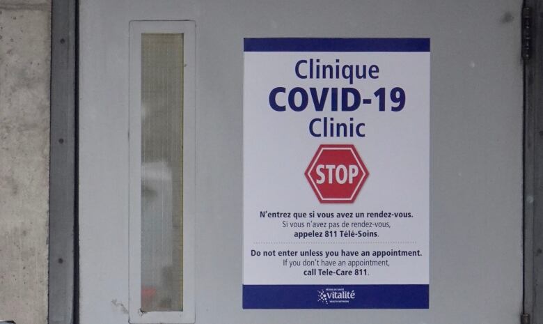 A door with a sign on it that says, in part, 'COVID-19 Clinic. Stop.'