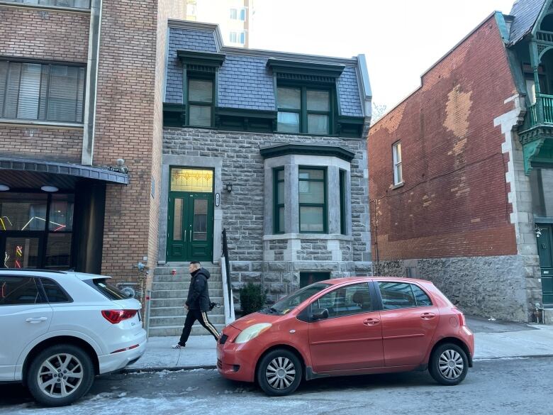 Two storey, Victorian house shown on residential downtown street.