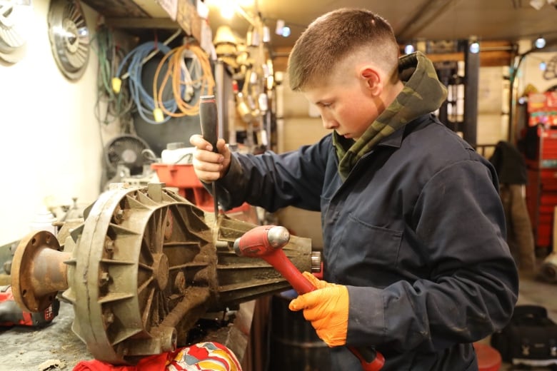 A student uses tools in an auto repair shop.