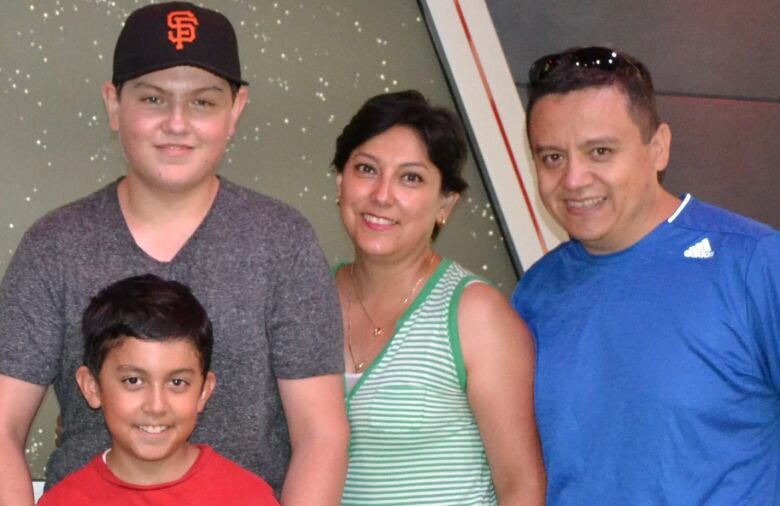 A family of four, including two boys, smile for the camera.