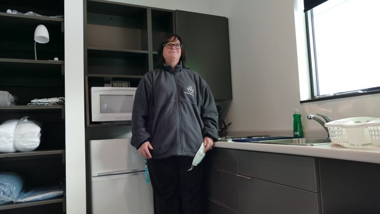 A woman is standing in a kitchen.