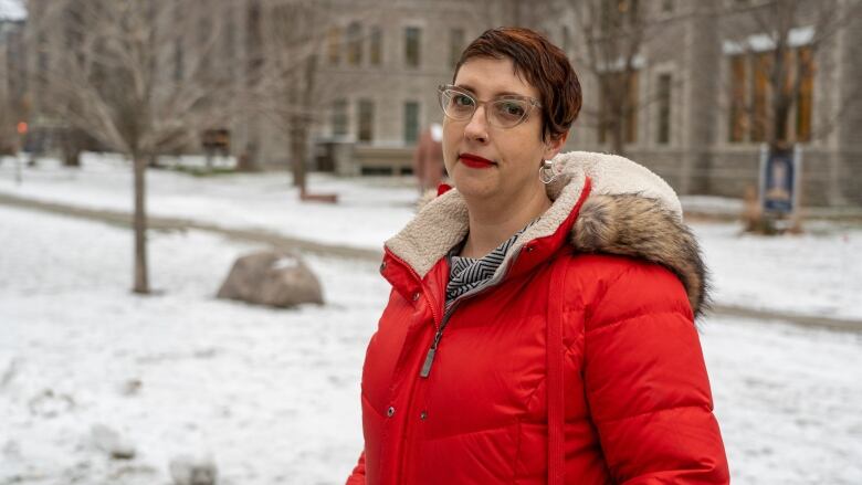 A politician in a winter coat poses for a photo outside in the snow.