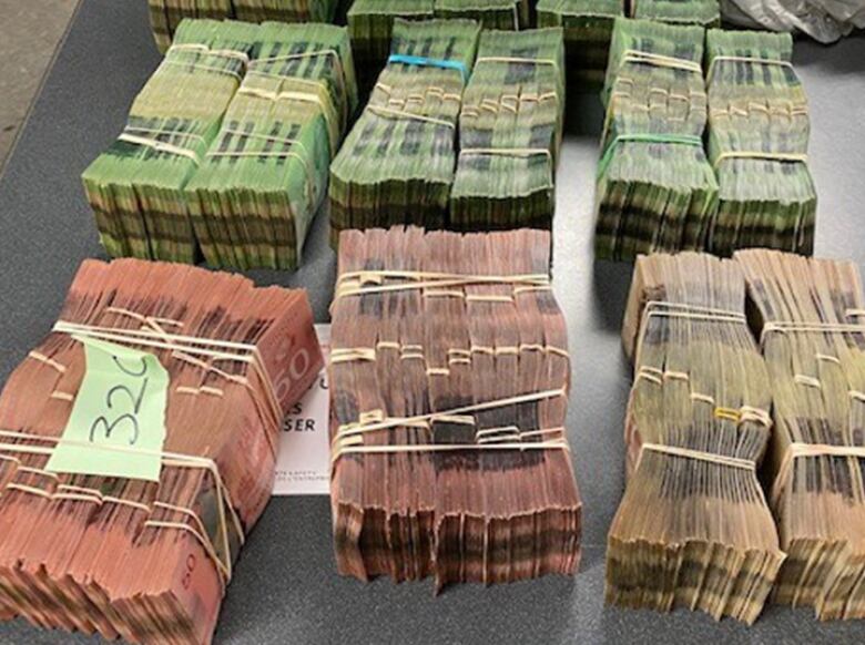 More than a dozen large stacks of Canadian dollar bills, wrapped tightly in rubber bands, lie on a table as evidence in Project Collector. 