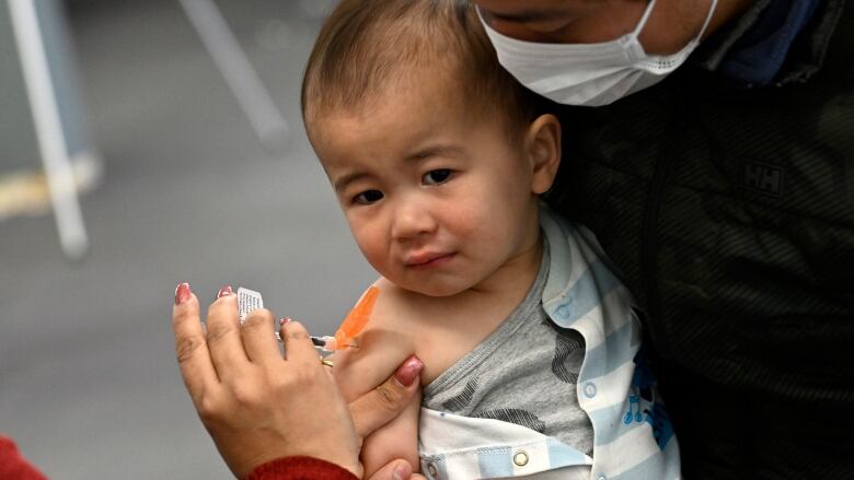 A child looks away tentatively as they get a needle.