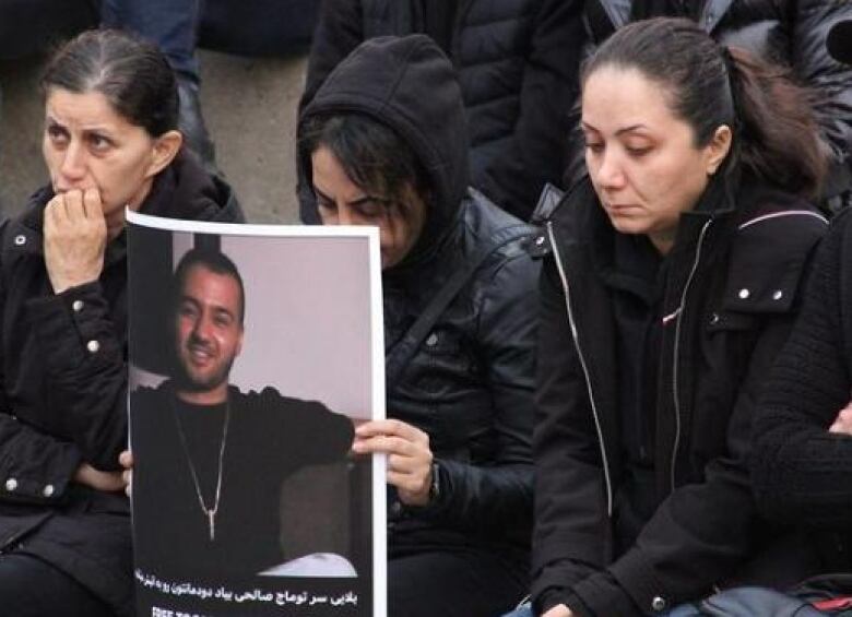 People wearing black hold a photo of the rapper Toomaj.