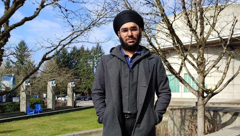 A South Asian man in a turban smiles for the camera in an outdoor environment.