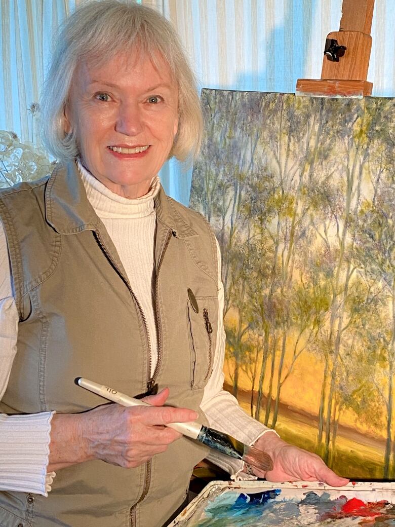 A woman stands next to an easel