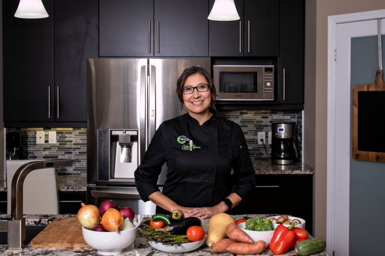 Chef Moser stands in her kitchen in front of a table full of fresh produce