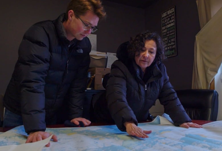 Two people look at a map of northwestern Ontario.