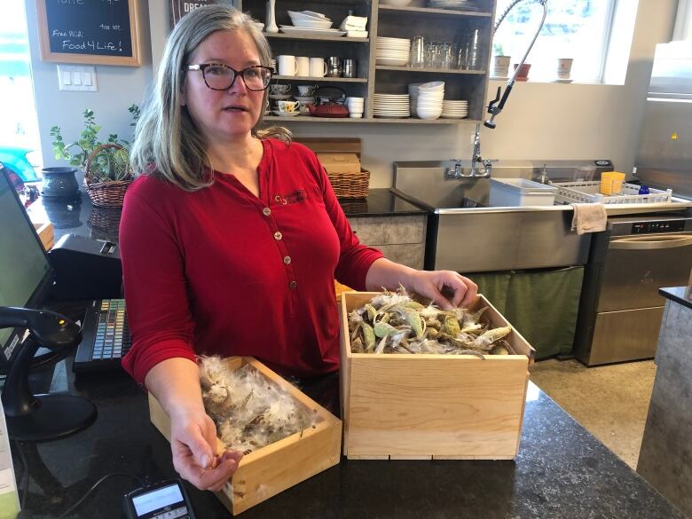 A woman in a red shirt with two boxes of garlic.