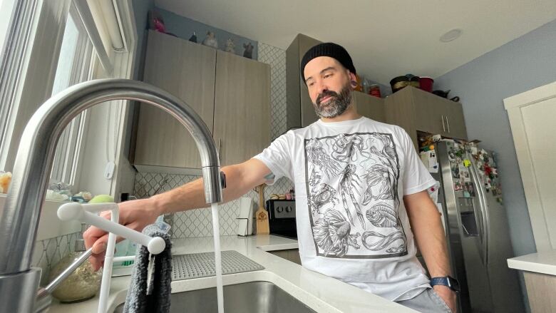 Kurtis Anderson turns on water from his kitchen faucet at his home in the south end of Regina on Nov. 25, 2022. 