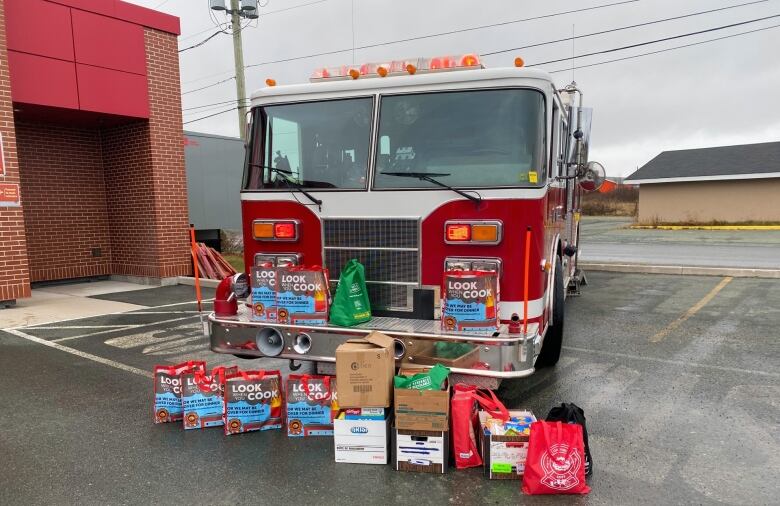 A firetruck sits in a parking lot in front of donations for a local food bank