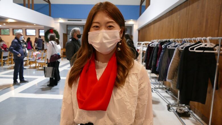 Woman smiles behind a mask in a building lobby.