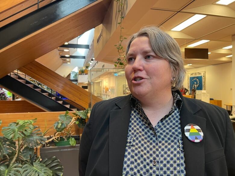 A woman stands talking in the lobby of an institutional building.