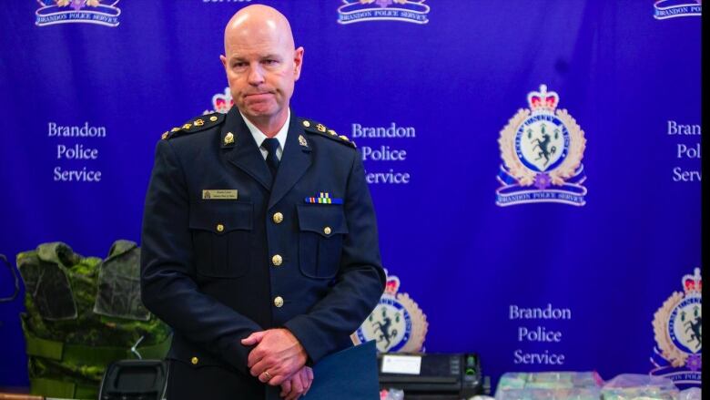 A man in a police uniform stands in front of a table with evidence on it.