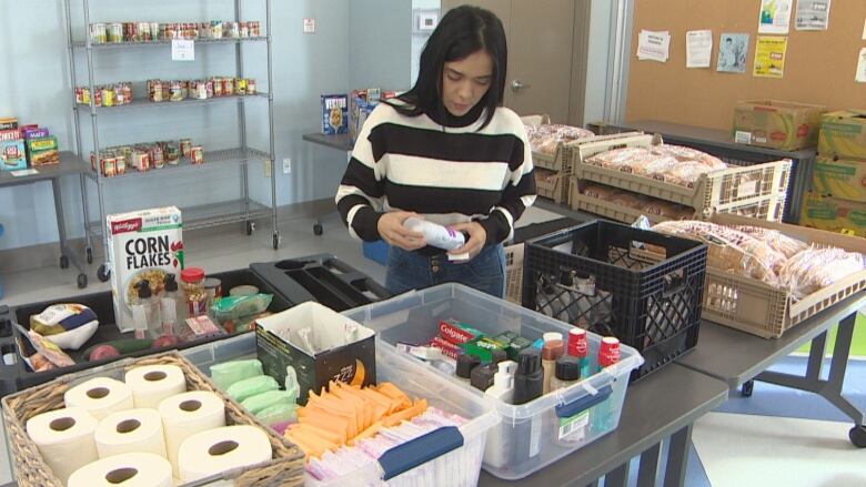 A woman picks up items from containers filled with toiletries.