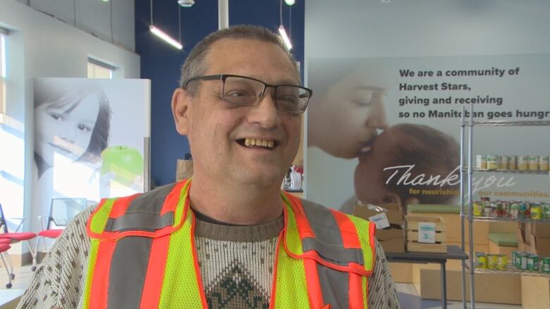 A man in a bright safety vest smiles.