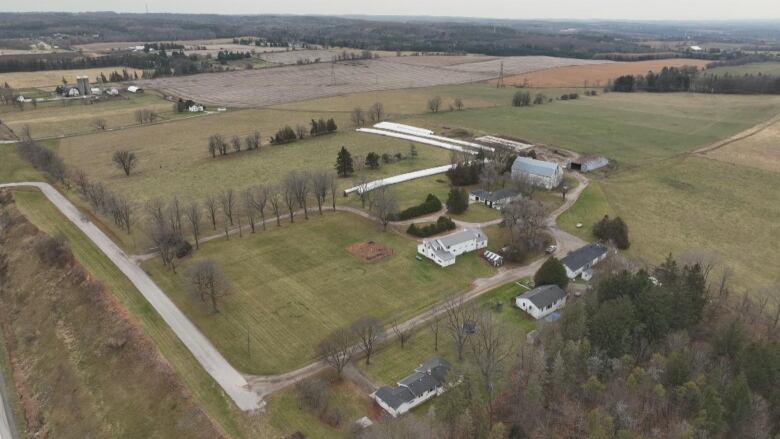 An aerial view of farmland showing fields, some houses and other buildings.