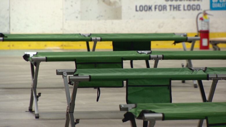 A close up of a row of cots on the floor of the arena. 