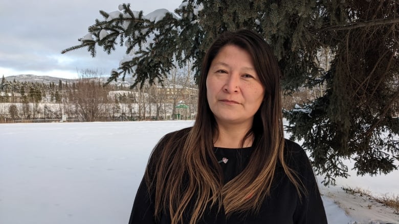 Woman standing infront of a tree outside in a park.