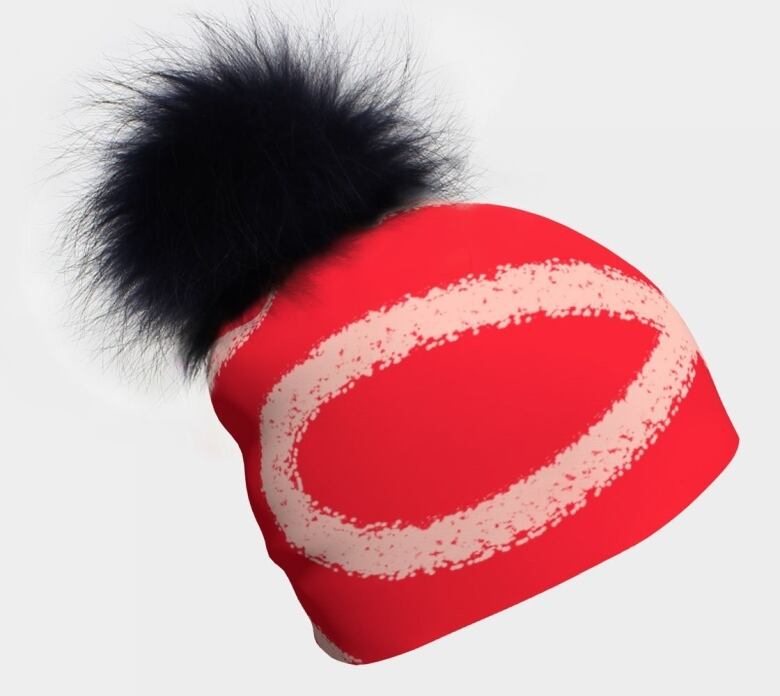 Photo of a red and pink printed beanie topped with a furry black pom pom.