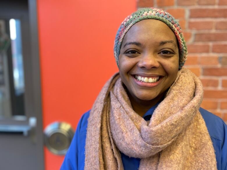 A woman, seen from the shoulders up, wearing a toque and a big scarf. 