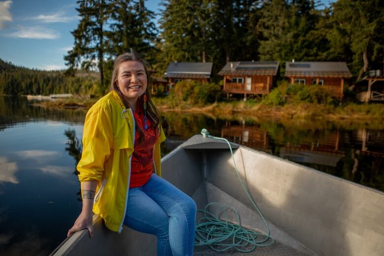 A woman sits on the edge of a boat next to three buildings with solar panels on the roof.