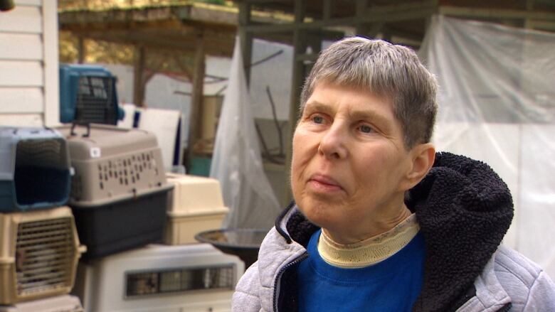 An old woman with short hair talks to a camera.