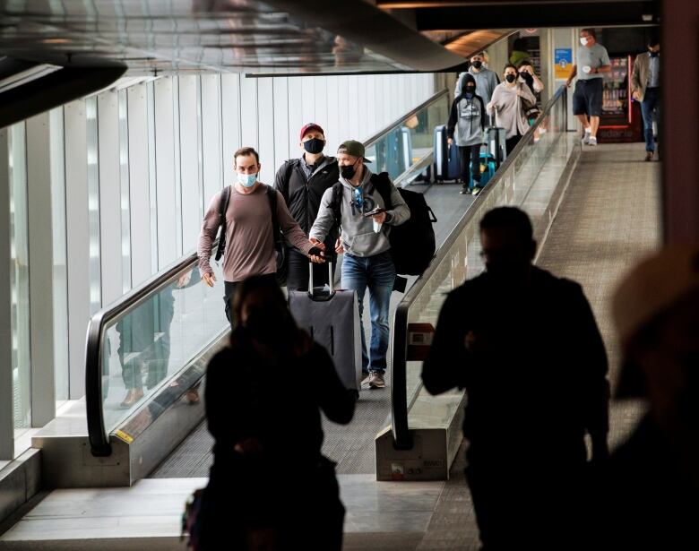 Masked passengers walk through Toronto's Pearson airport. 