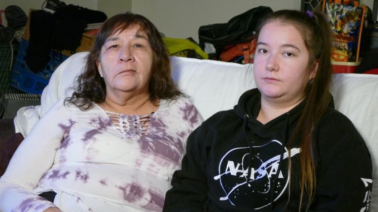 Two women sit close together on a couch.