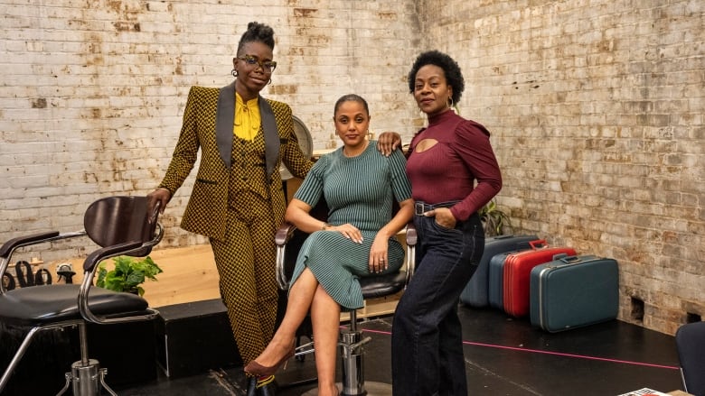 Two people stand on either side of a chair with a person sitting in it. 