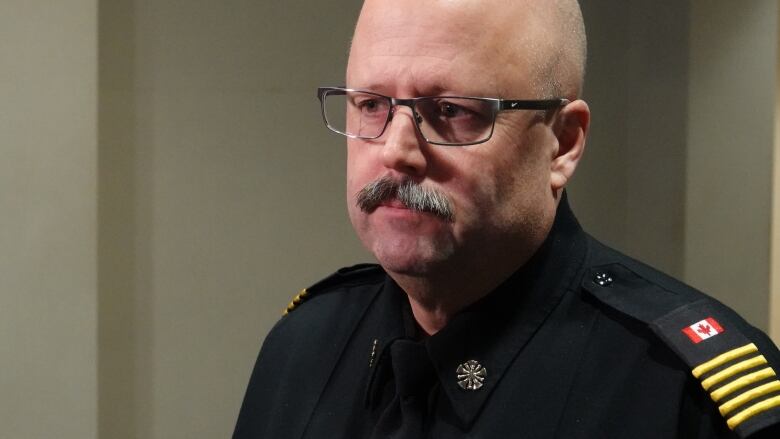 A man with a mustache and glasses wearing a fire department uniform, seen from the shoulders up.