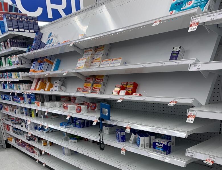 Pharmacy store shelves with boxes of cold and flu medication.