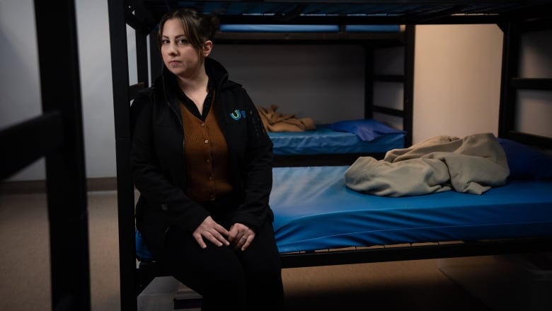 A woman sits on a bunk bed.