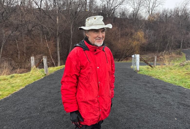 A man with a bright red jacket and a bucket hat stands at the bottom of the escarpment below St-Jacques Street.