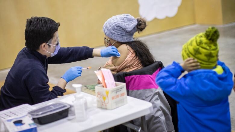 A child receives her influenza vaccine with her family at a Fraser Health vaccination clinic in Surrey, B.C., on Wednesday, Dec. 7, 2022. 