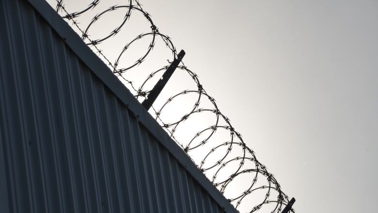 Rings of razor wire line the top of a steel wall at the Sudbury Jail 