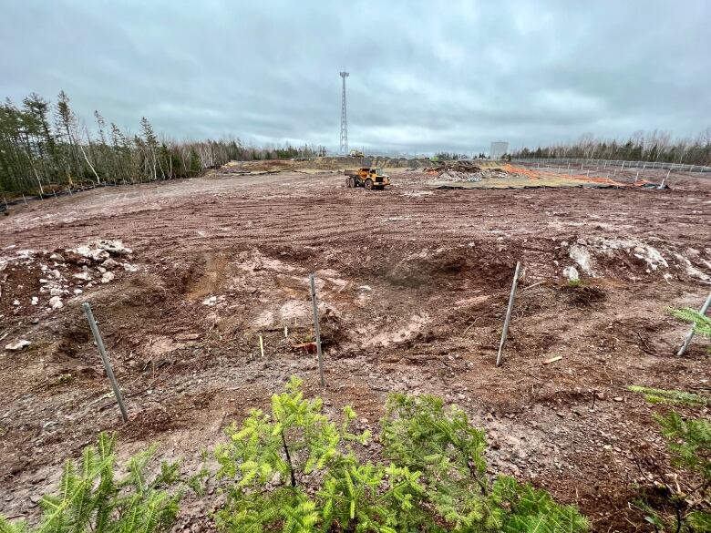 A muddy field is seen with a constructive vehicle seen in the distance.