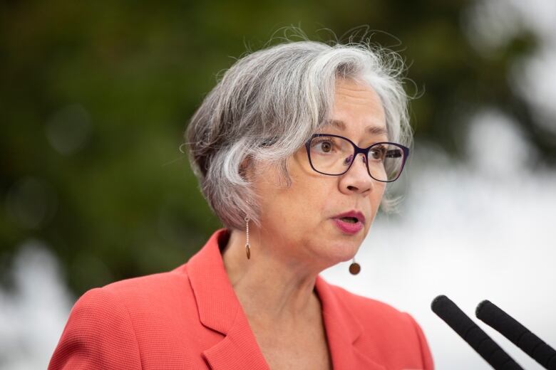 Jennifer Whiteside, a white woman with short grey hair, speaks at a podium.