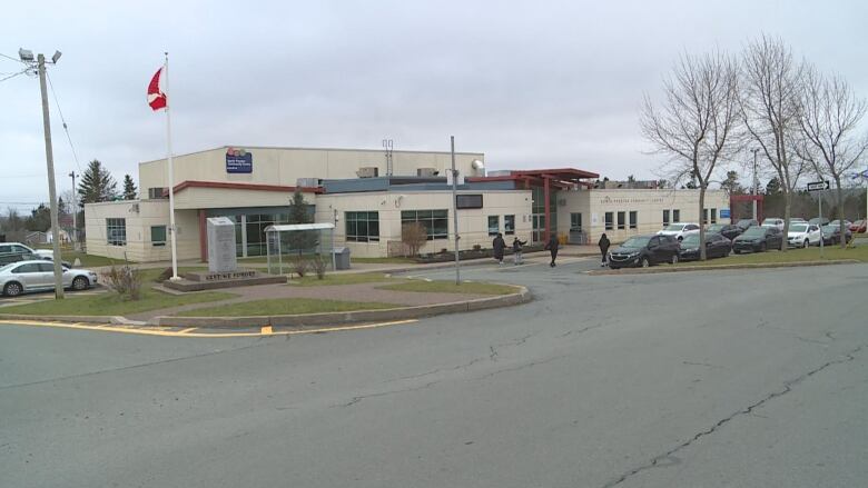 A low beige coloured building beside a parking lot