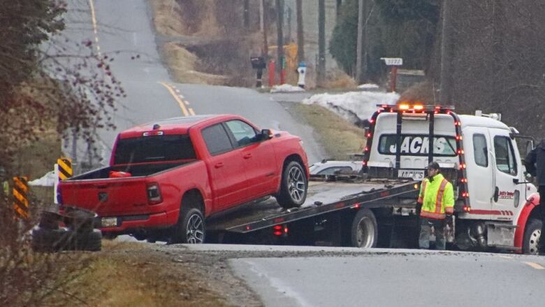 A red Dodge pickup truck is seen being towed away.