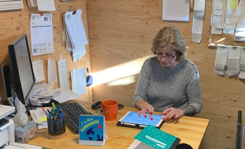 A woman at a desk using an iPad. 